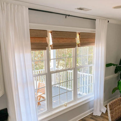 Close-up of bamboo roman shades in a fully raised position showing clean folds.