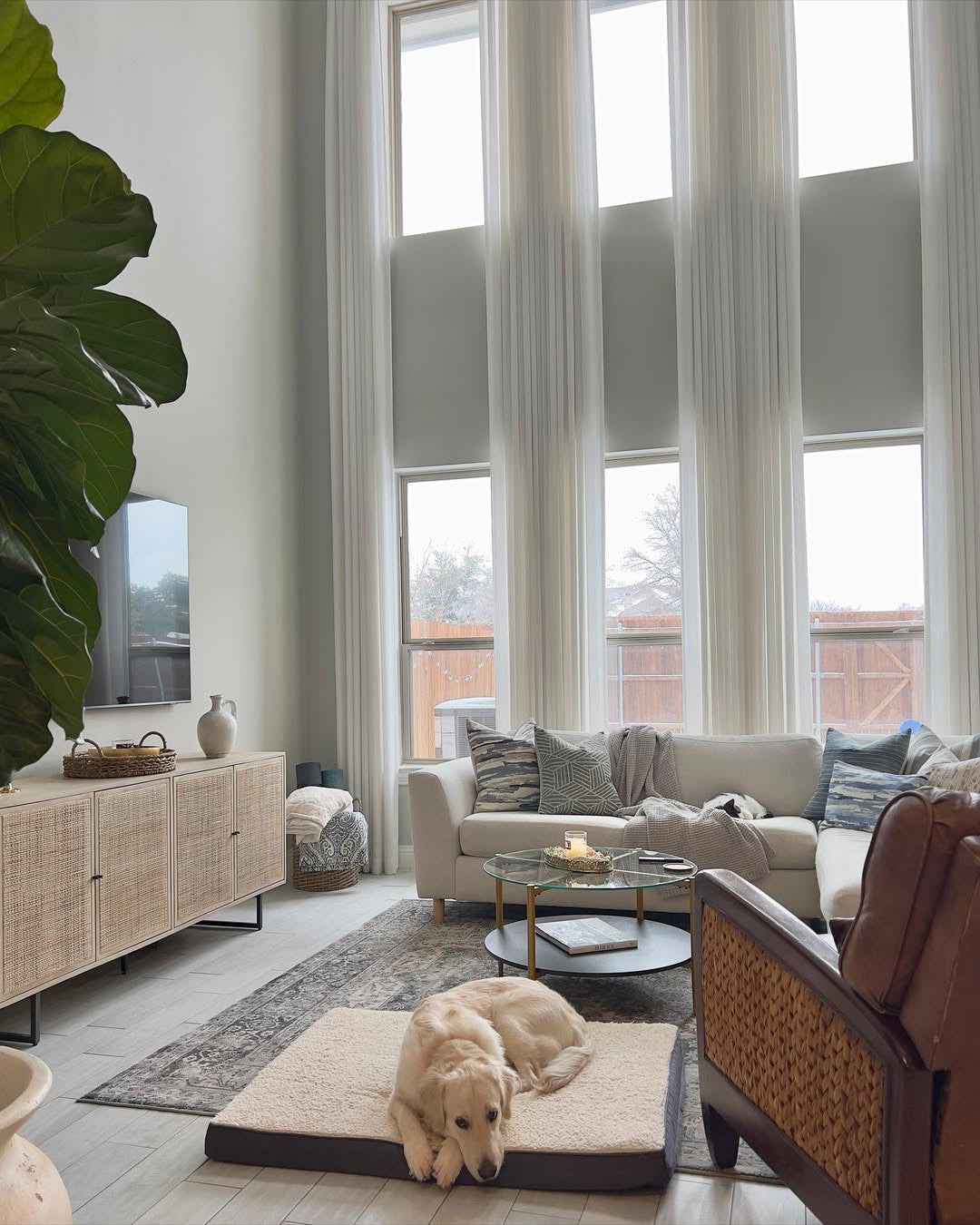 Extra-long custom white pinch pleat linen curtains installed in a high-ceiling living room for a grand look