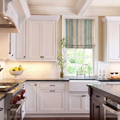 Custom striped linen roman shade in a white farmhouse kitchen, installed over a classic apron-front sink.