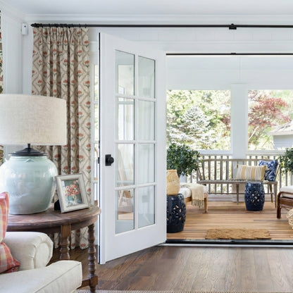 Vintage red floral drapes in a rustic farmhouse living room featuring wooden furniture and light filtering effects.